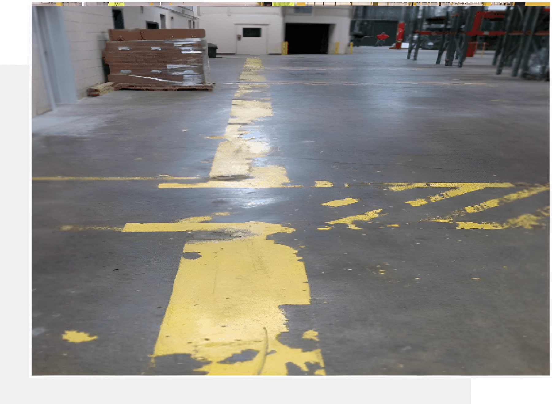 Here's an alt tag for the image: Worn yellow floor markings in warehouse.