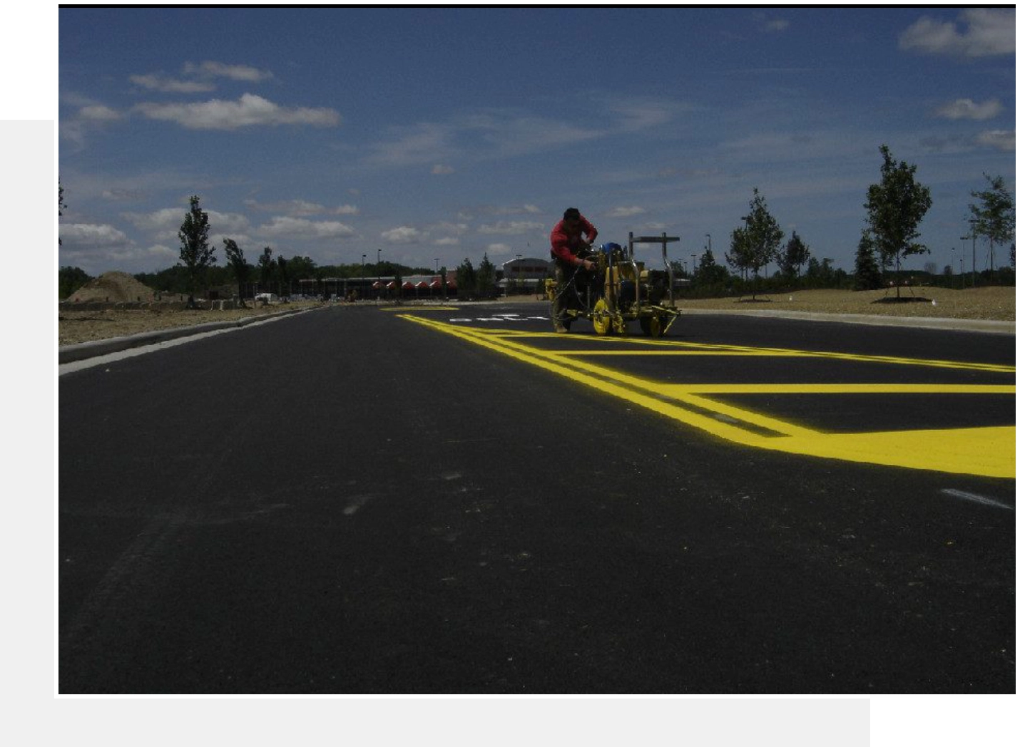 Worker painting yellow lines on new road.